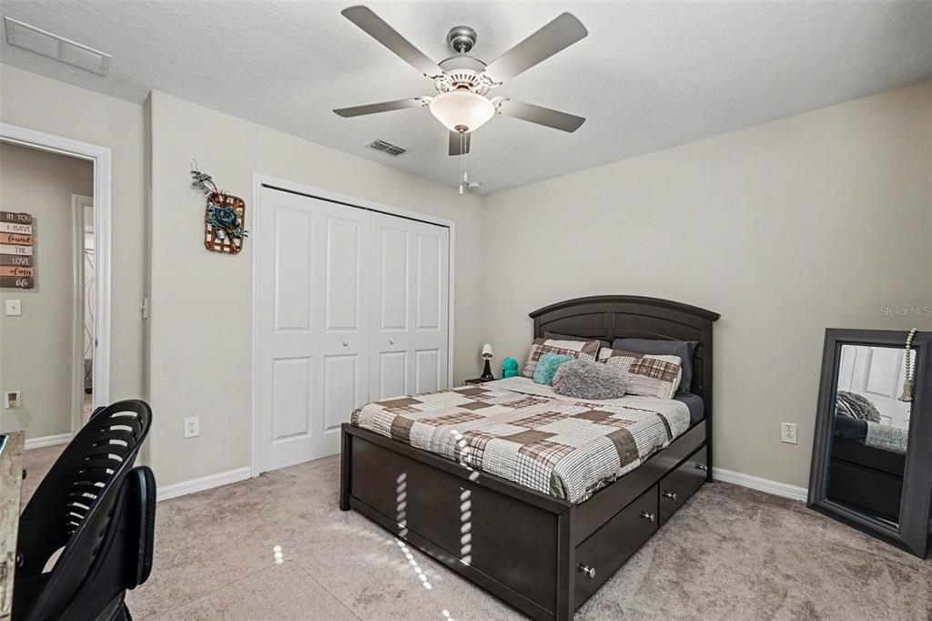 9424 Lemon Drop Loop Sun City Center, FL 33573 - Photo 24 of 31 a bedroom with a bed and a chandelier