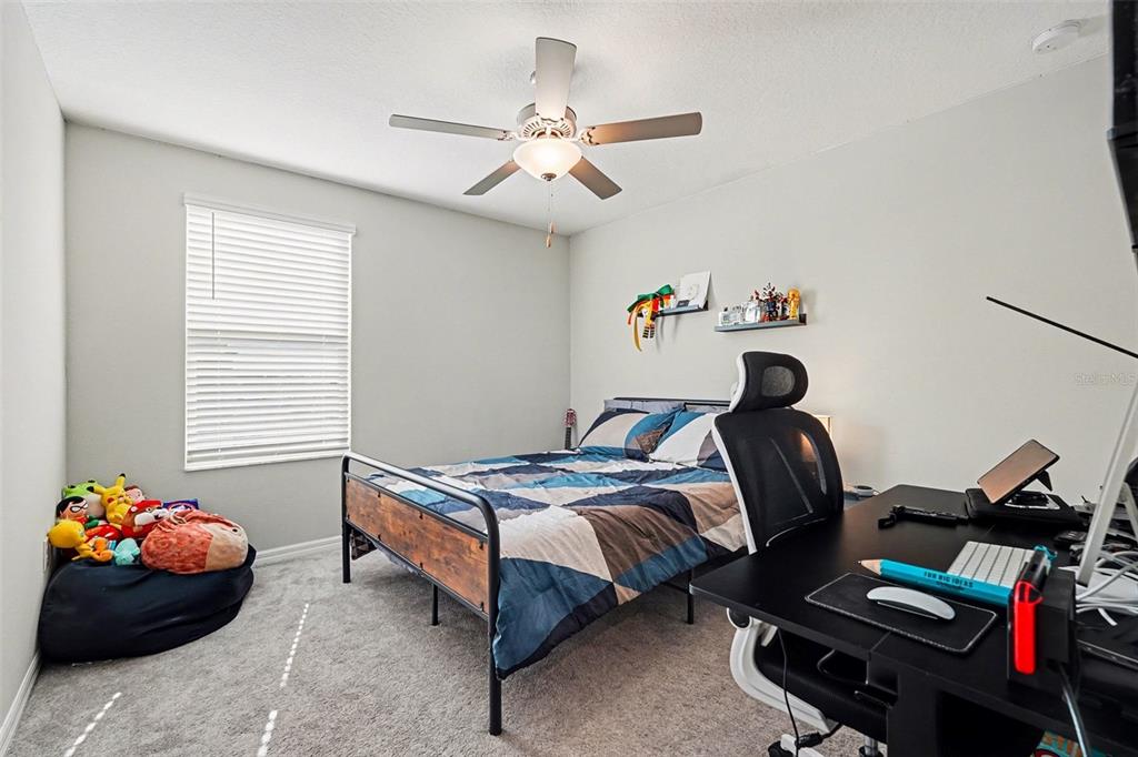 9424 Lemon Drop Loop Sun City Center, FL 33573 - Photo 25 of 31 a bedroom with a bed and a chandelier