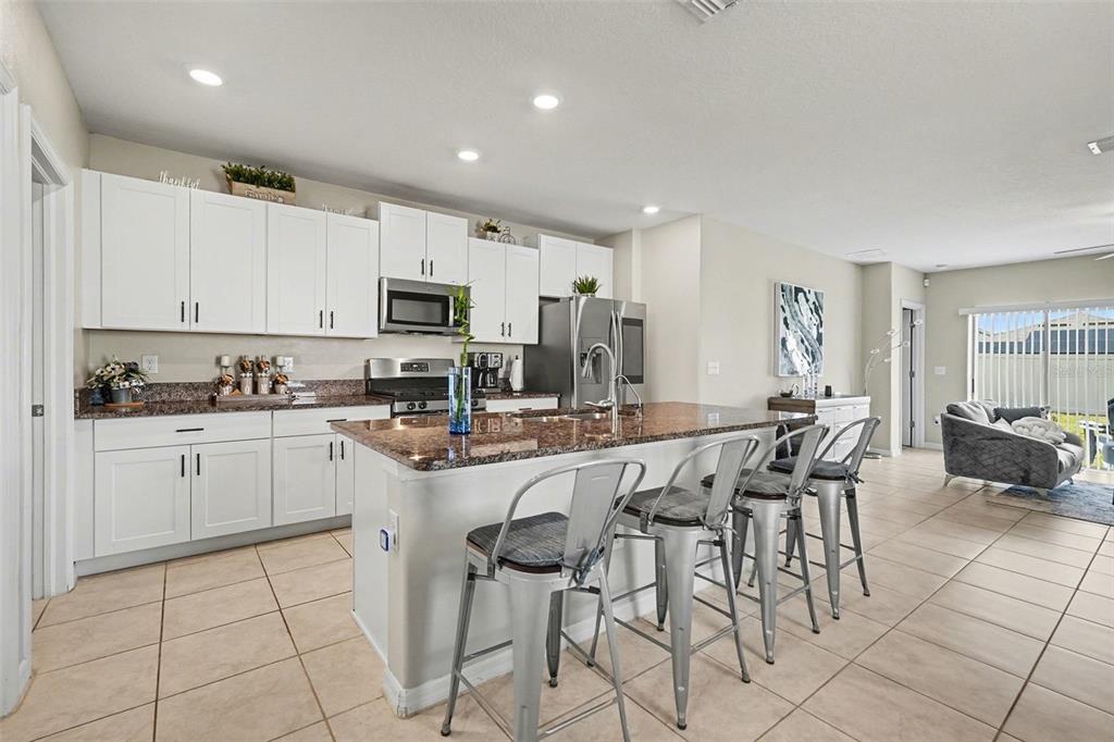9424 Lemon Drop Loop Sun City Center, FL 33573 - Photo 4 of 31 a kitchen with stainless steel appliances granite countertop a stove a sink a microwave a dining table and chairs