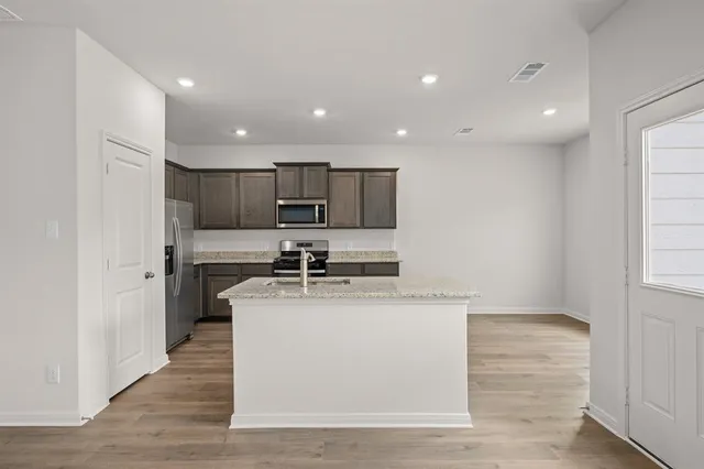 a kitchen with stainless steel appliances granite countertop a sink dishwasher a refrigerator and a stove with wooden floor