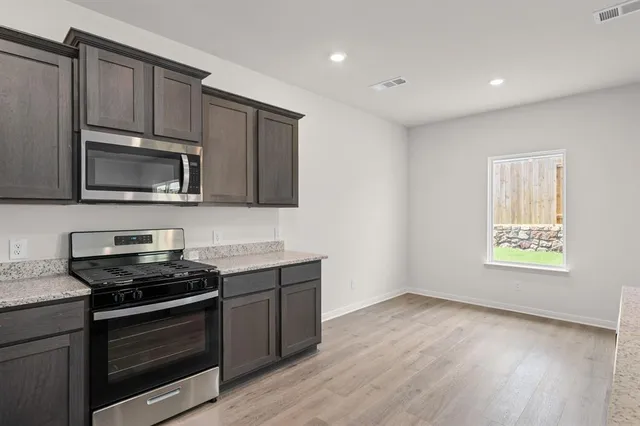 a kitchen with granite countertop a stove and a microwave