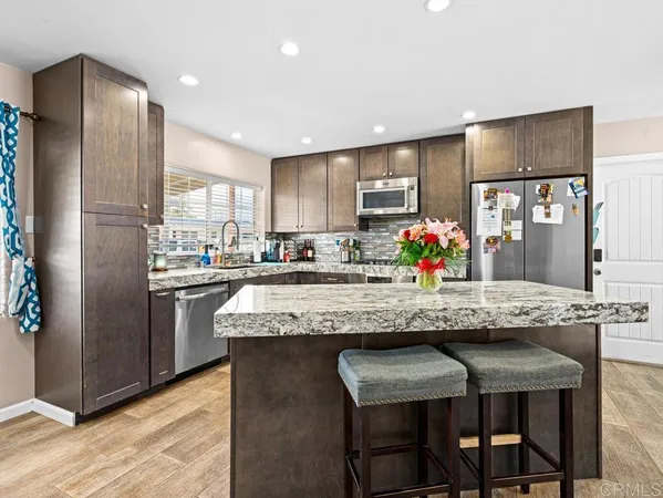 a kitchen with stainless steel appliances granite countertop table chairs refrigerator and microwave
