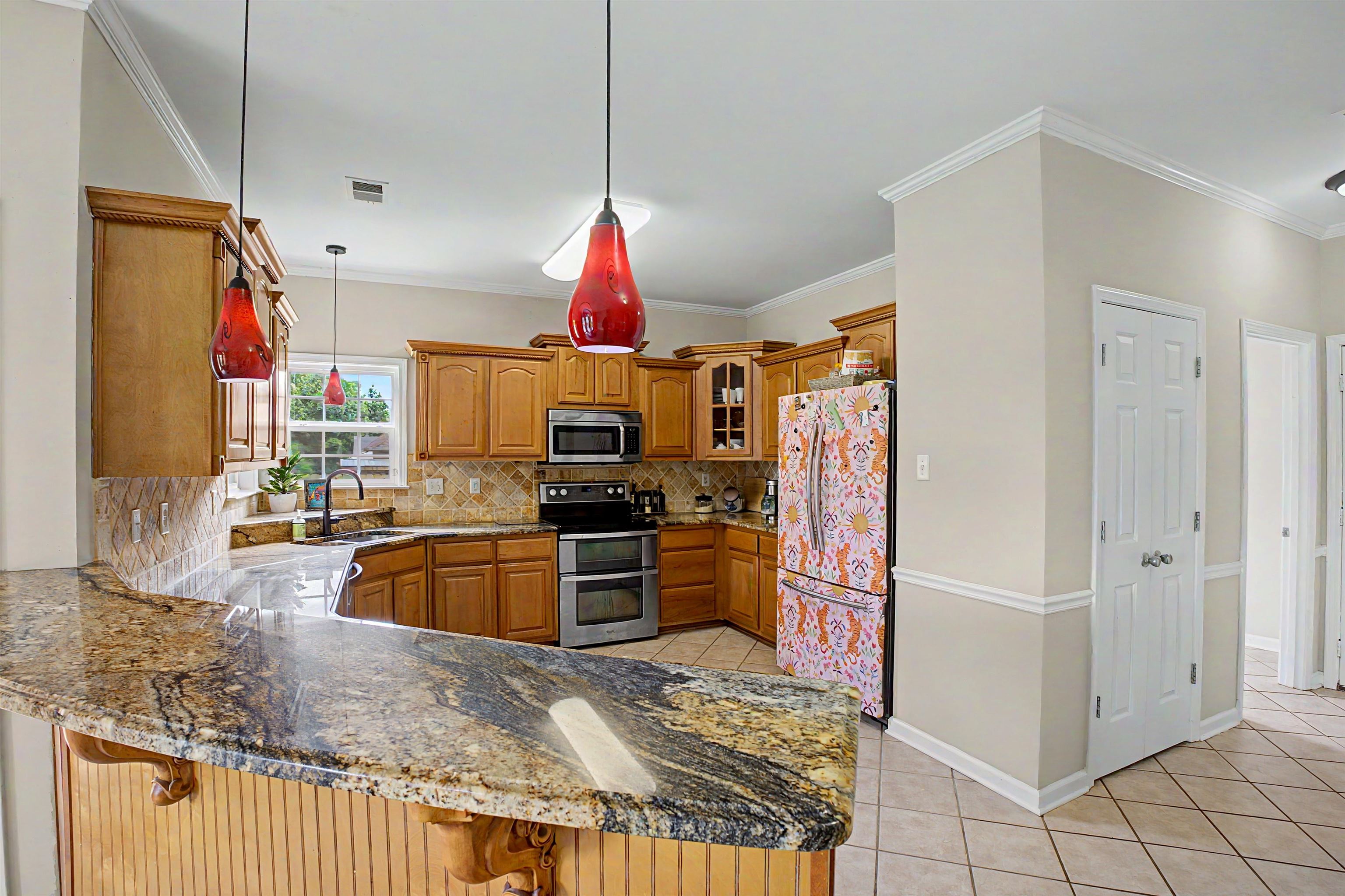 134 Rembert Drive Atoka, TN 38004 - Photo 18 of 38 Spacious kitchen featuring an extended bar-height countertop with wood-finish paneling, light wood cabinetry, and a double wall oven