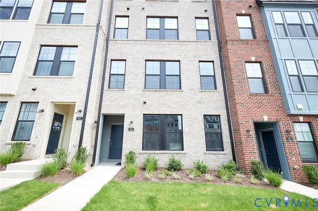 front view of a brick house with a yard and large windows