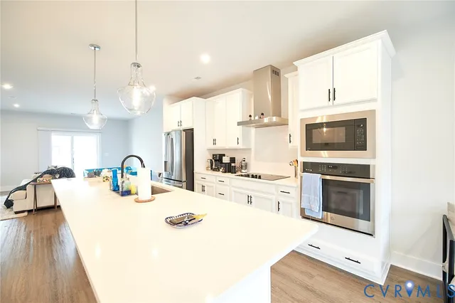 a kitchen with kitchen island a stove a sink a refrigerator and a fireplace with wooden floor