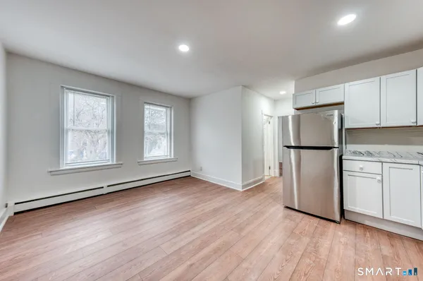 a view of an empty room with a kitchen and a window