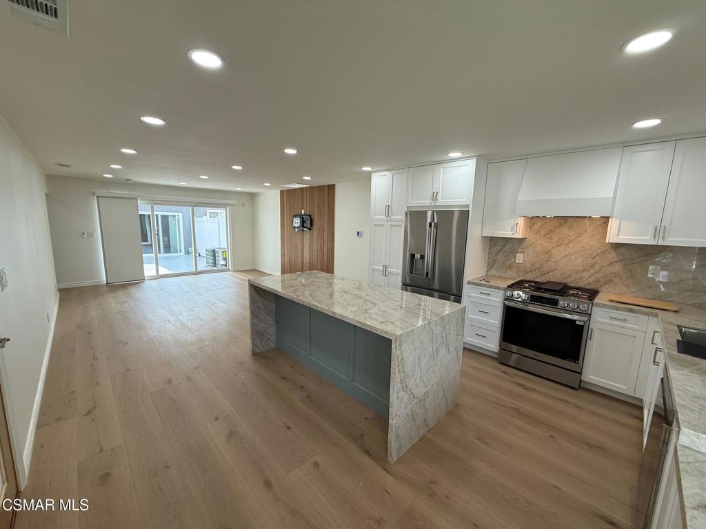 a large kitchen with stainless steel appliances granite countertop a large counter top and a stove top oven