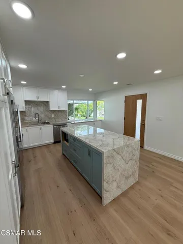 a large kitchen with stainless steel appliances granite countertop a large counter top and wooden floors
