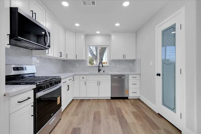a kitchen with stainless steel appliances granite countertop a stove a sink and a microwave