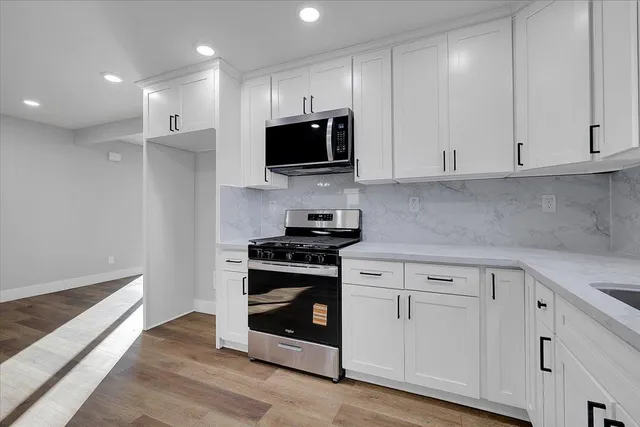 a kitchen with stainless steel appliances granite countertop a stove a microwave and white cabinets