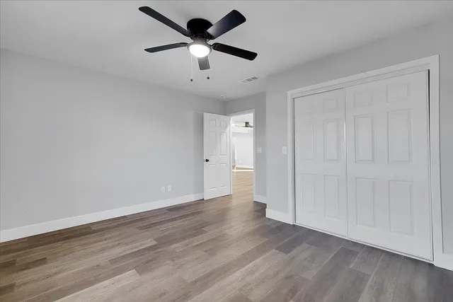 an empty room with wooden floor and ceiling fan