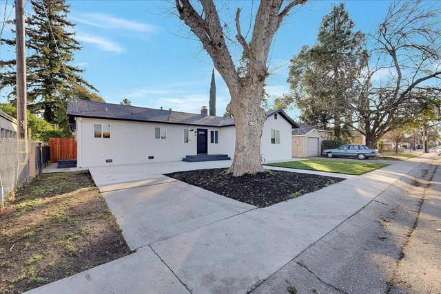 a view of a white house with a yard and large tree