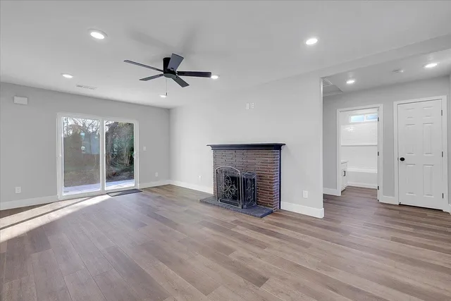 an empty room with wooden floor fireplace and windows