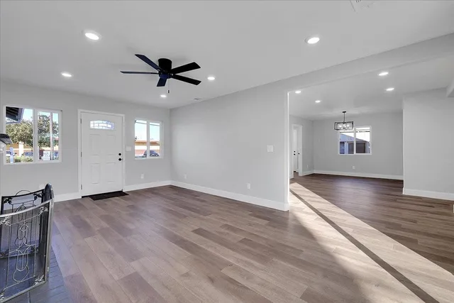 an empty room with wooden floor and windows