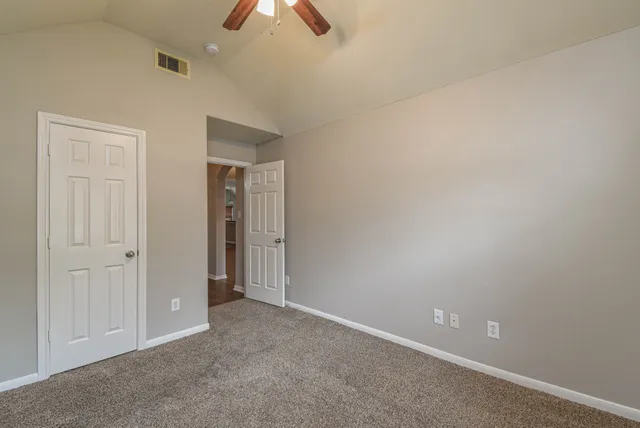 an empty room with closet and fan
