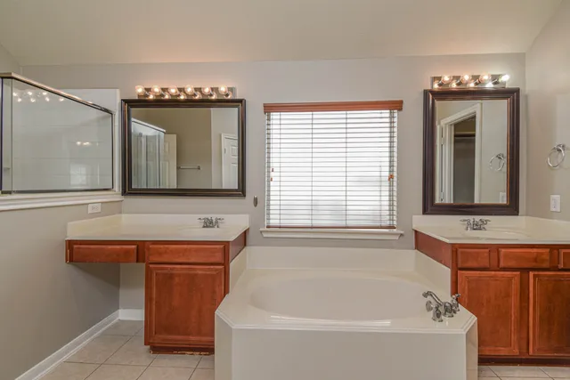 a bathroom with a bathtub a sink and a large mirror