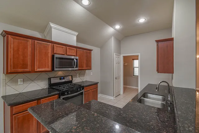 a kitchen with stainless steel appliances granite countertop a sink stove and microwave