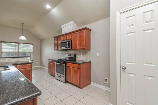 a kitchen with stainless steel appliances granite countertop a stove a sink and a refrigerator