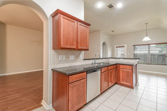 a large kitchen with granite countertop a sink and cabinets