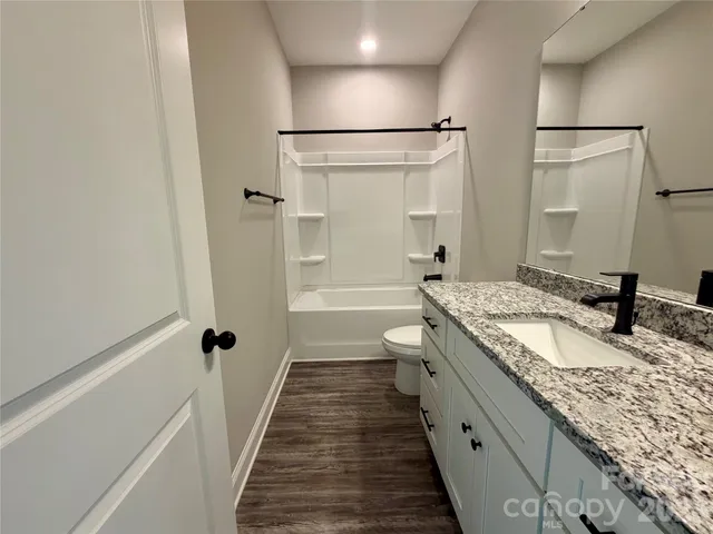 a bathroom with a granite countertop sink a toilet and shower