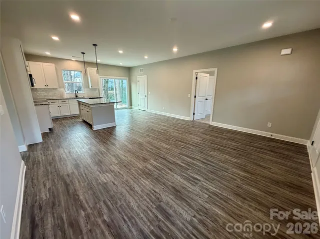 a view of kitchen and empty room with wooden floor