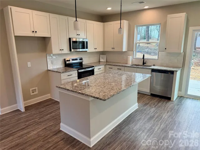 a kitchen with stainless steel appliances granite countertop a sink a stove and a wooden floors