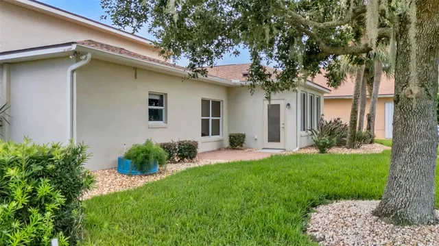 a view of a white house with a yard and potted plants