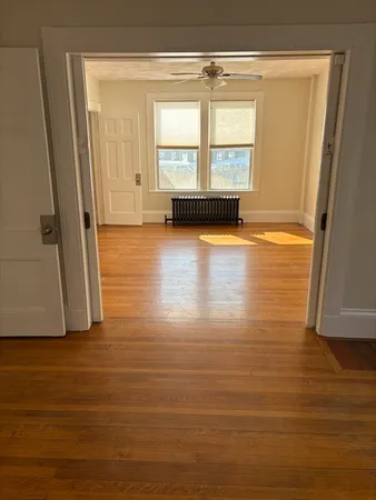 a view of an empty room with wooden floor and a window