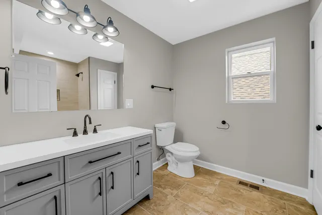 a bathroom with a toilet sink a mirror and vanity