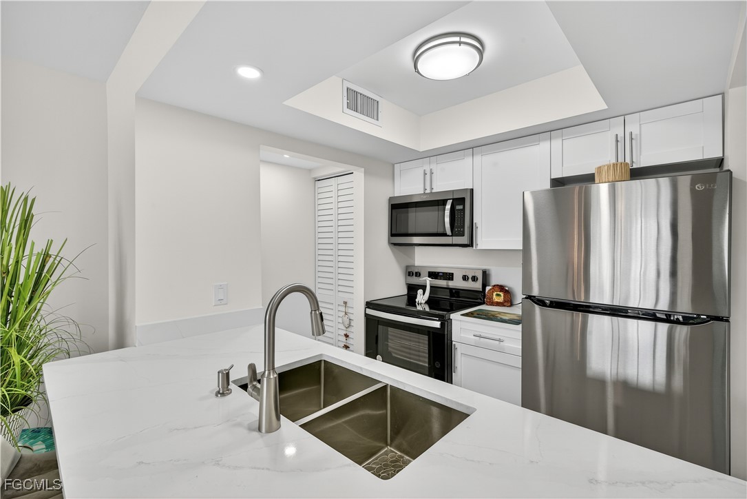 200 Lenell Road, Unit 214 Fort Myers Beach, FL 33931 - Photo 14 of 32 a kitchen with a refrigerator sink and stainless steel appliances