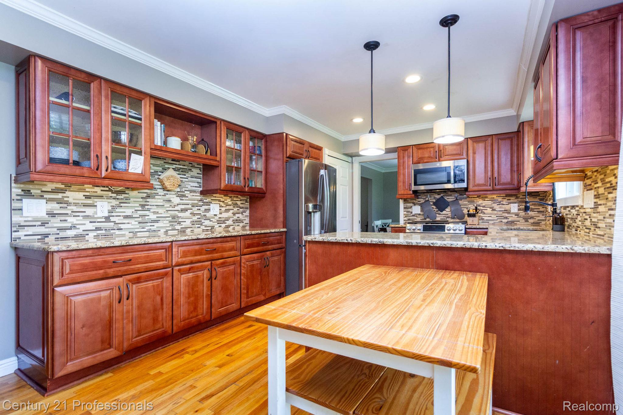 671 Bridgestone Drive Rochester, MI 48309 - Photo 12 of 50 Kitchen featuring wood cabinetry, granite countertops, a mosaic tile backsplash, stainless steel appliances, and wood-finish flooring