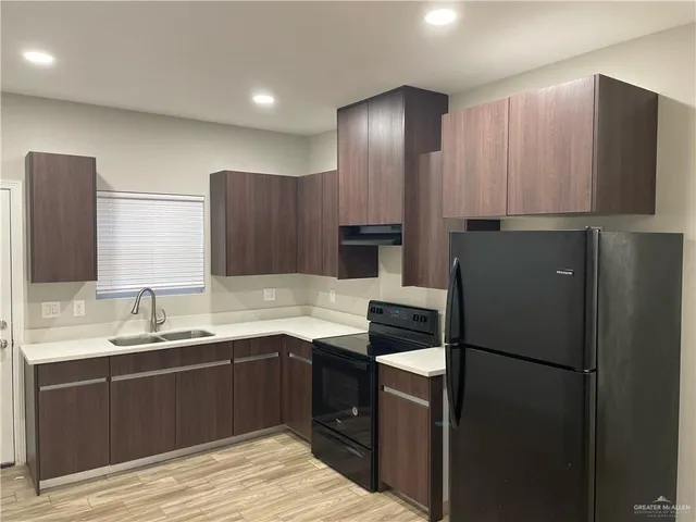 a kitchen with a sink refrigerator and cabinets