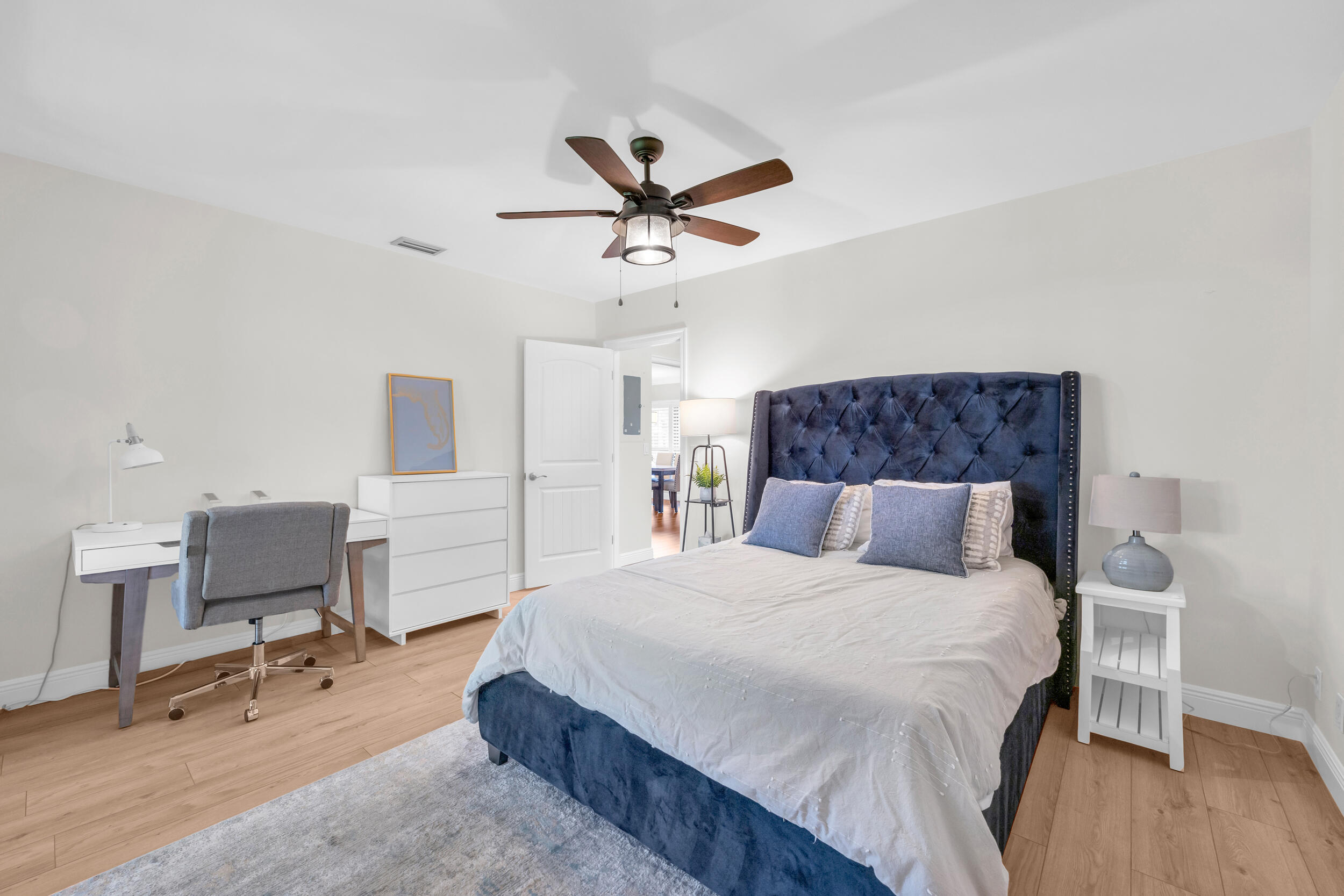 8 Southeast Turtle Creek Drive, Unit D Jupiter, FL 33469 - Photo 24 of 33 a bedroom with a bed a desk and chair with wooden floor