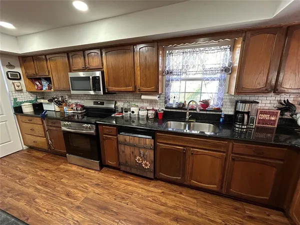 a kitchen with stainless steel appliances granite countertop a stove a sink dishwasher and a microwave oven with cabinets