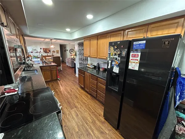a kitchen with stainless steel appliances granite countertop sink stove refrigerator and wooden floor