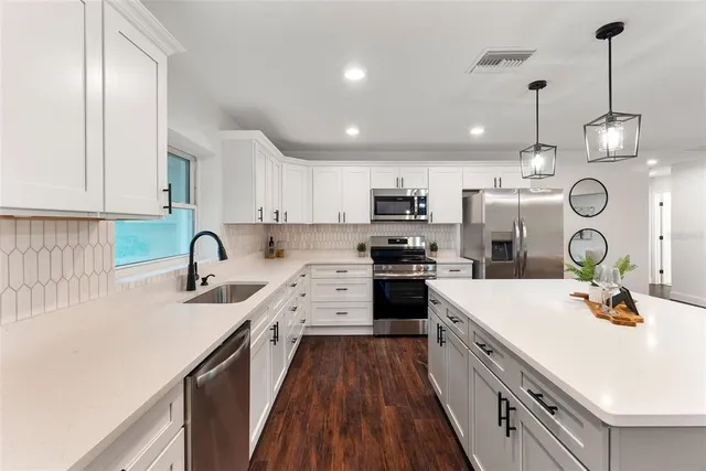 a kitchen with kitchen island granite countertop a sink a stove a refrigerator cabinets and a dining table