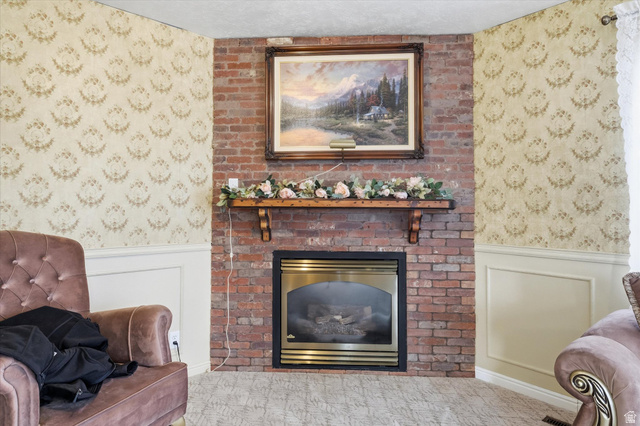 165 Main Street Georgetown, ID 83239 - Photo 6 of 50 Living room with wallpapered walls, wainscoting, a decorative wall, a fireplace, and carpet flooring
