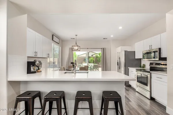 a kitchen with stainless steel appliances kitchen island granite countertop a table chairs microwave and sink