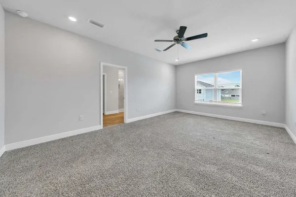 an empty room with windows and ceiling fan