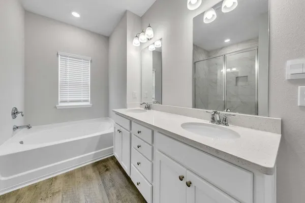 a spacious bathroom with a bathtub double sink and mirror