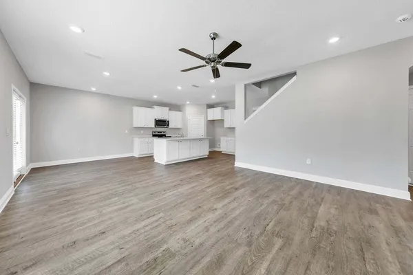 a view of kitchen with stainless steel appliances refrigerator stove and wooden floor