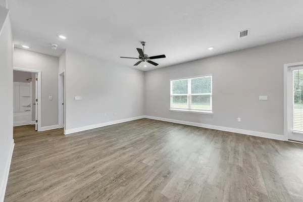 a view of an empty room with a window and wooden floor
