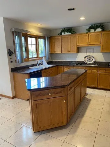 a kitchen with granite countertop a stove a sink a counter top space and cabinets