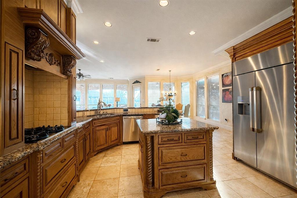 1919 Kings Pass Heath, TX 75032 - Photo 12 of 38 The kitchen features hardwood cabinetry, granite countertops, tile flooring, and a central island with additional storage