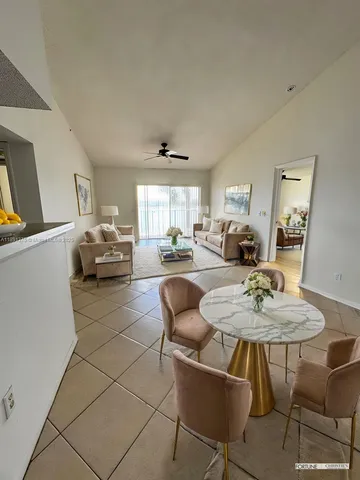 a living room with furniture a table and kitchen view