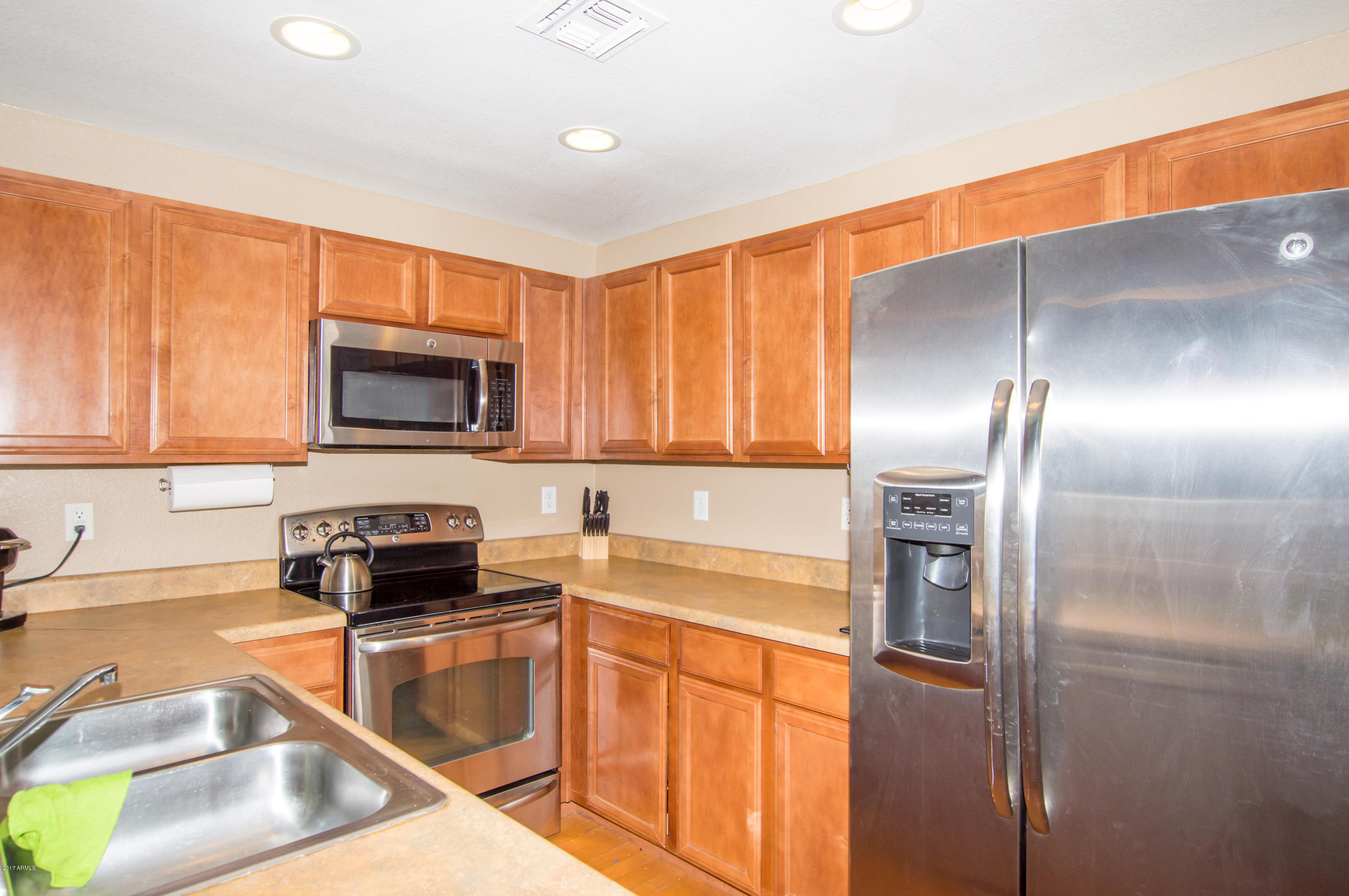3150 East Beardsley Road, Unit 1016 Phoenix, AZ 85050 - Photo 3 of 25 a kitchen with stainless steel appliances granite countertop a refrigerator a stove and a sink with wooden floor