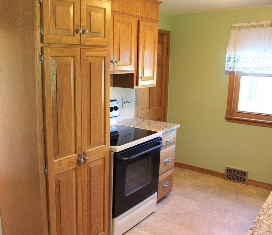 32 Randall Street Chicopee, MA 01013 - Photo 9 of 28 a kitchen with stainless steel appliances granite countertop a sink a washer and dryer with wooden cabinets