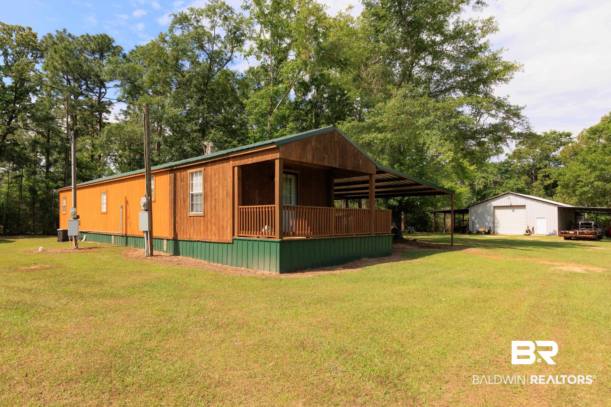 6725 Upper Creek Road Flomaton, AL 36441 - Photo 24 of 61 View of property exterior featuring a detached garage, a yard, an outbuilding, and view of scattered trees