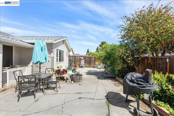 a view of a patio with table and chairs potted plants and a large tree