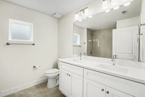 a bathroom with a toilet a sink a mirror a vanity and window